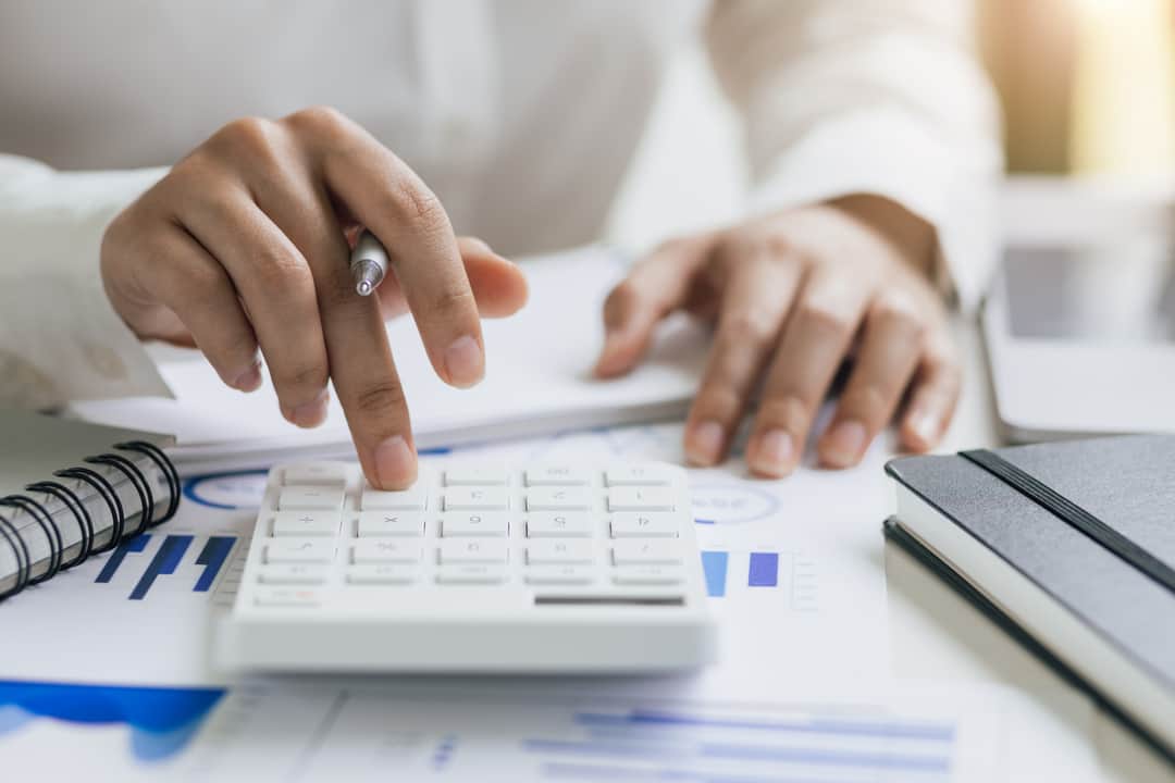 Businesswoman analyzing company financial accounts and planning budget allocation using calculator.