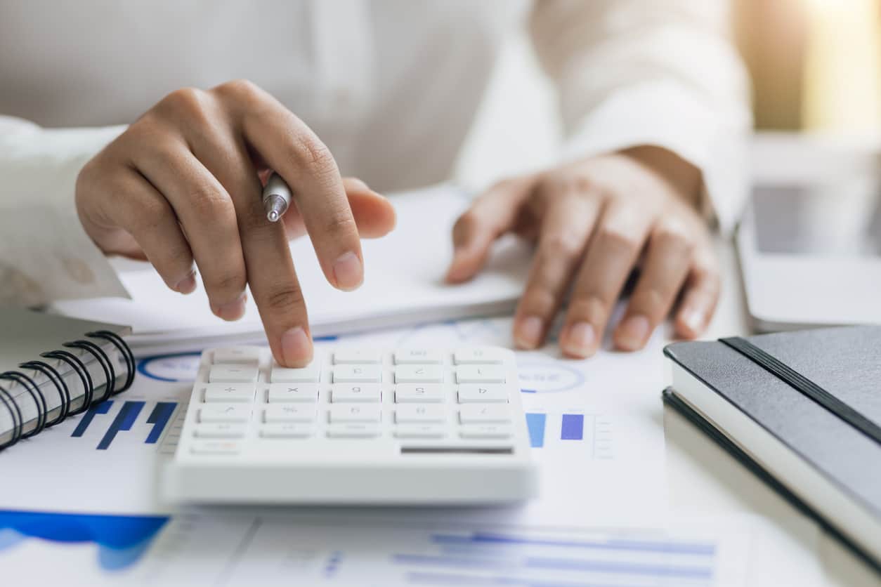 Businesswoman analyzing company financial accounts and planning budget allocation using calculator.