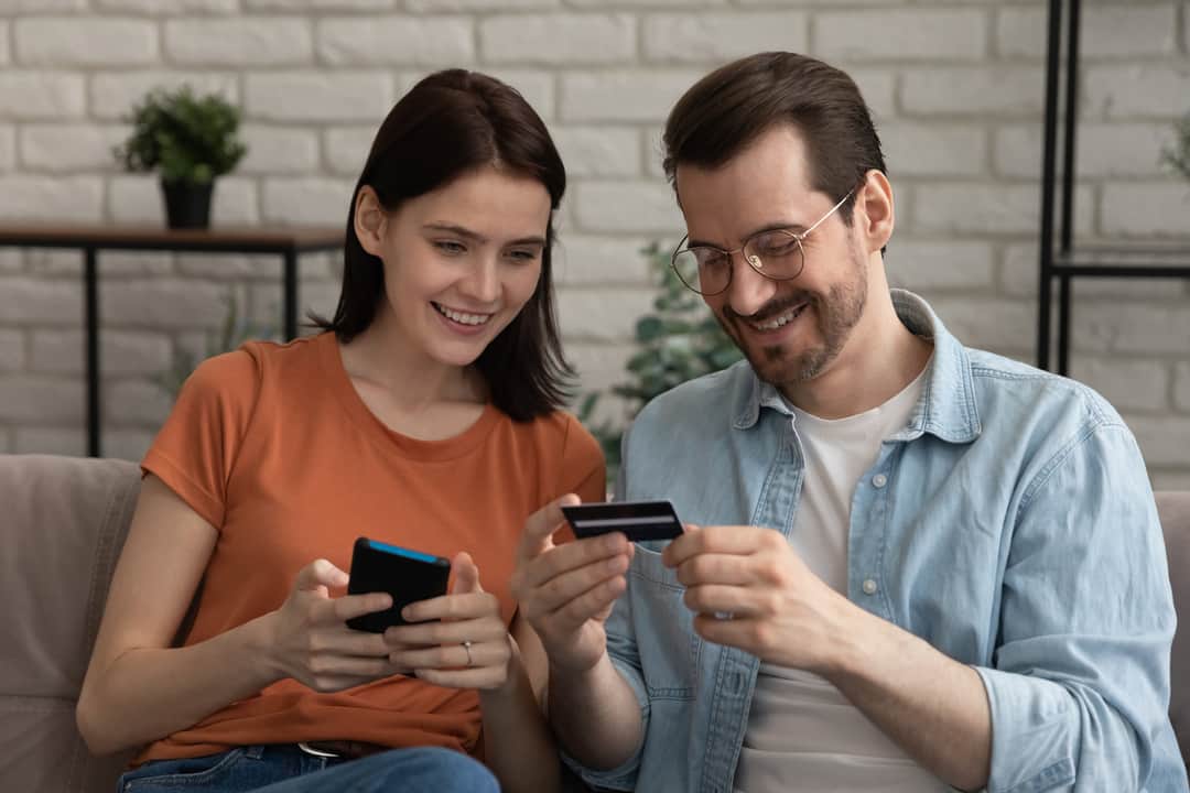 Smiling millennial caucasian couple shopping in mobile application.