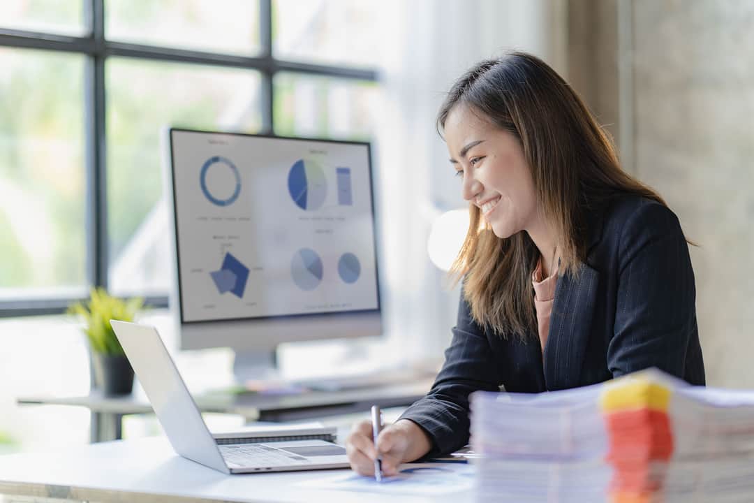 Asian businesswoman with chart or document at work using business laptop calculator financial accountant calculating money